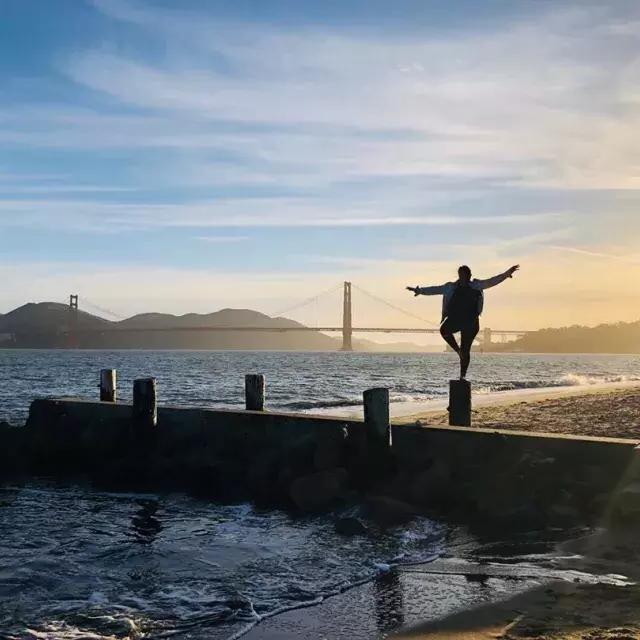一名妇女站在贝博体彩app码头附近的码头上, looking out at the Golden Gate Bridge.